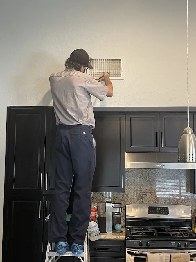 Technician inspecting an air vent during HVAC service in Bell Gardens